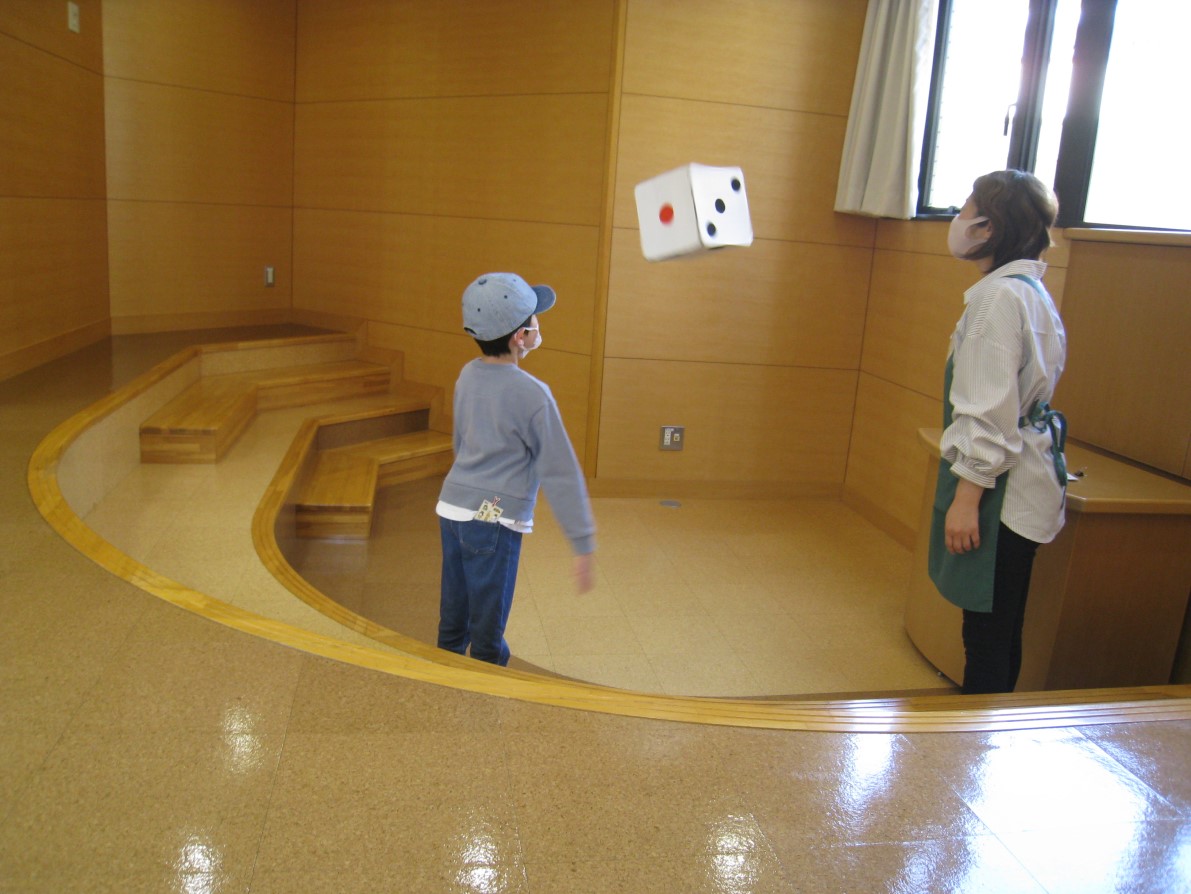 大きいサイコロを振る様子